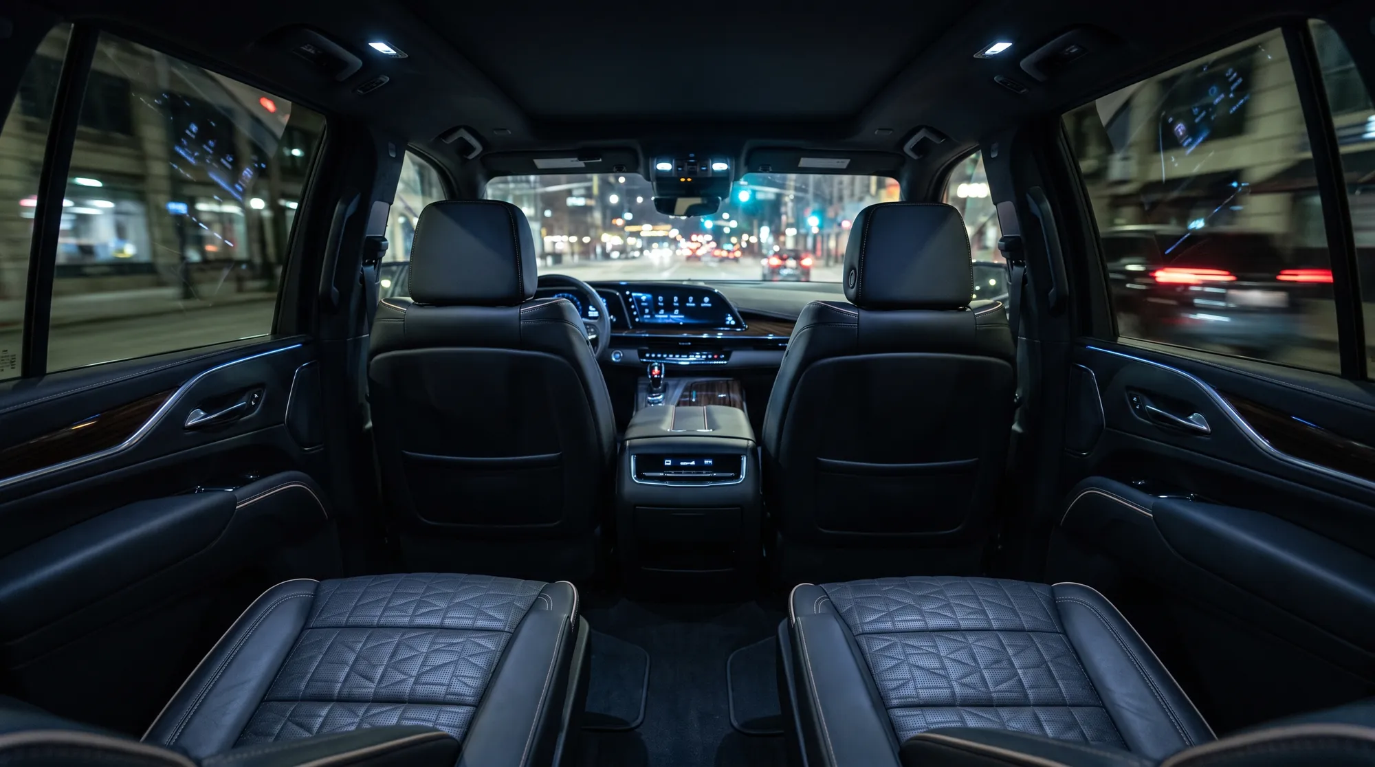 Rear seats and curved display inside a Cadillac Escalade ESV at night
